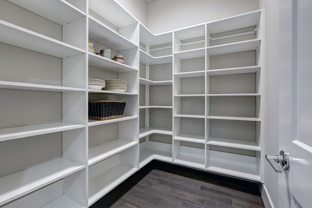 Empty pantry interior with white shelves and dark wood floor